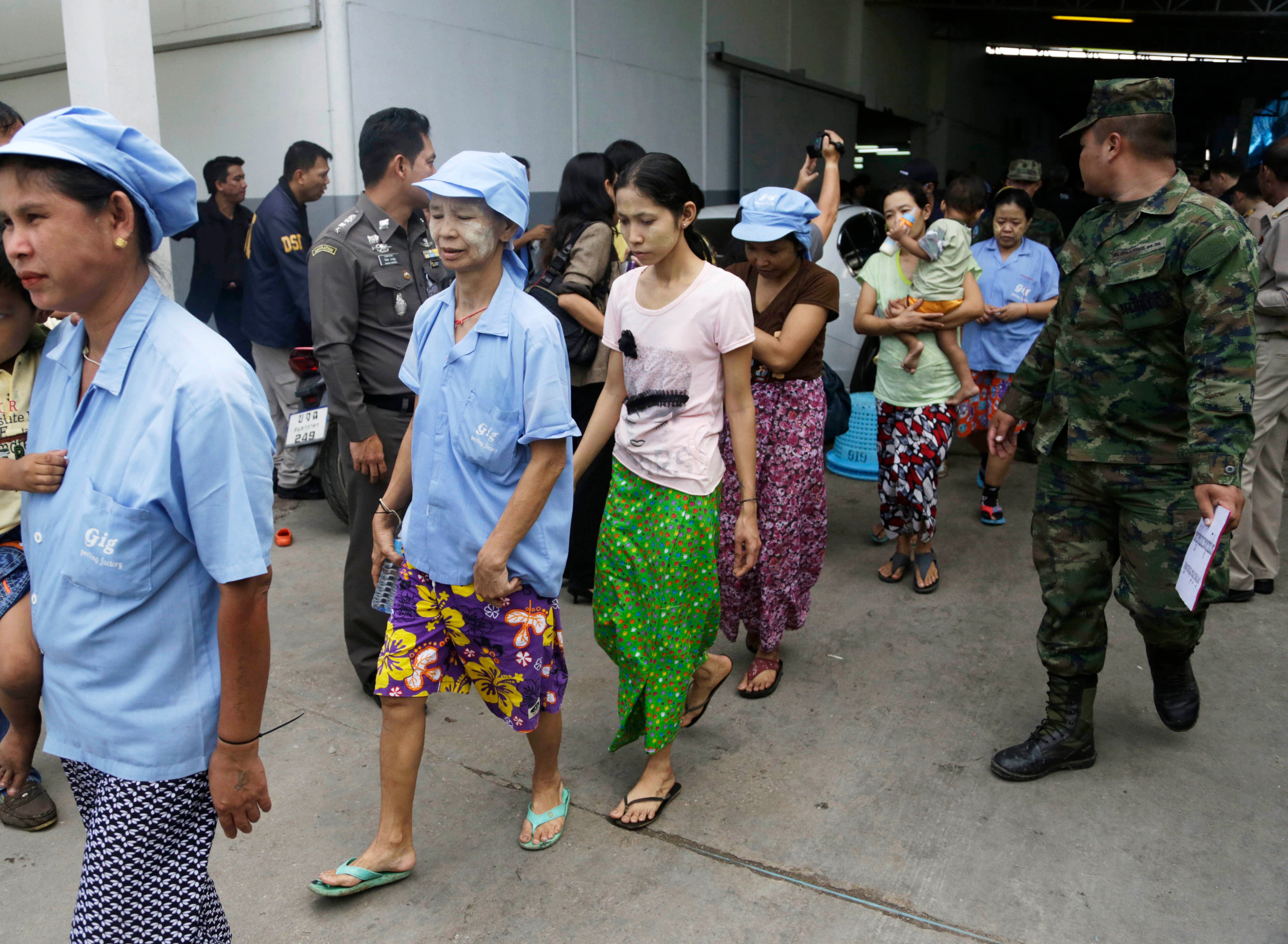 In this Monday, Nov. 9, 2015 photo, Burmese workers are escorted by soldiers and police officers as they leave a shrimp shed after a raid conducted by Thailand's Department of Special Investigation in Samut Sakhon, Thailand. (AP)