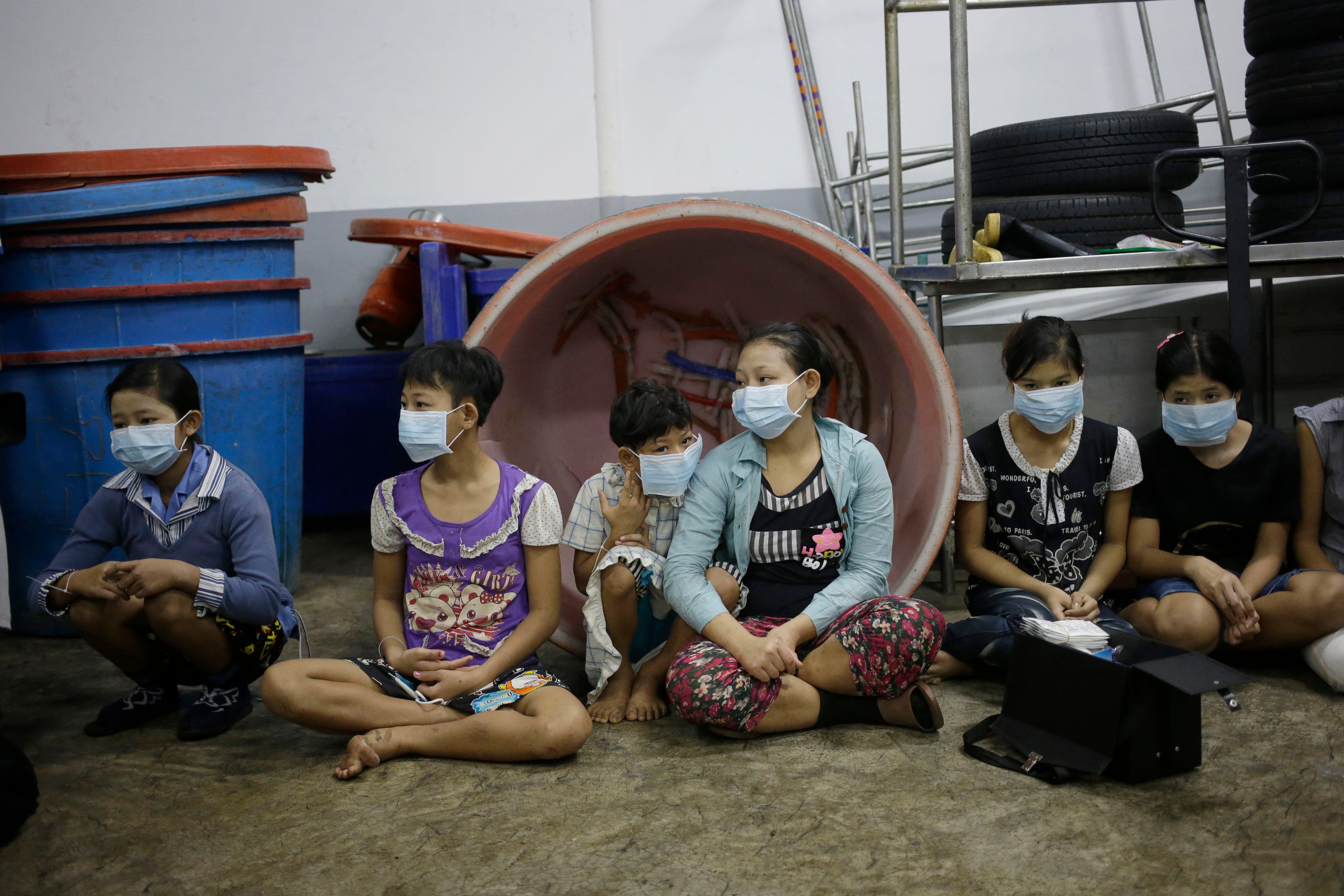 In this Monday, Nov. 9, 2015 photo, children and teenagers sit together to be registered by officials during a raid on a shrimp shed in Samut Sakhon, Thailand.