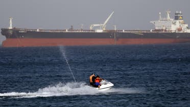 A couple rides a jetski past the Egyptian crude oil tanker "Sharifa 4" near the beach in El Ain El Sokhna port in Suez before the tanker enters the Suez Canal, east of Cairo, Egypt, July 26, 2015.  (Reuters)