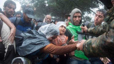 n this photo taken on Thursday, Sept. 10, 2015, Macedonian border police helps refugees and migrants to pass in heavy rainfall from the northern Greek village of Idomeni to southern Macedonia. (AP)