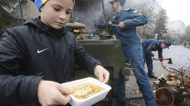 boy carries a container with soup as he visits a mobile station, opened and operated by members of the Russian Emergencies Ministry to lend support and to distribute hot meals among local residents due to power cuts in the settlement of Massandra, Crimea, November 27, 2015. 