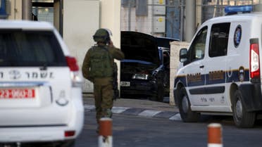 An Israeli soldier stands in front of a car (C) used by a Palestinian man in what an Israeli police spokesman said was a car ramming attack at the Qalandiya checkpoint between Jerusalem and the West Bank, December 18, 2015. (Reuters)