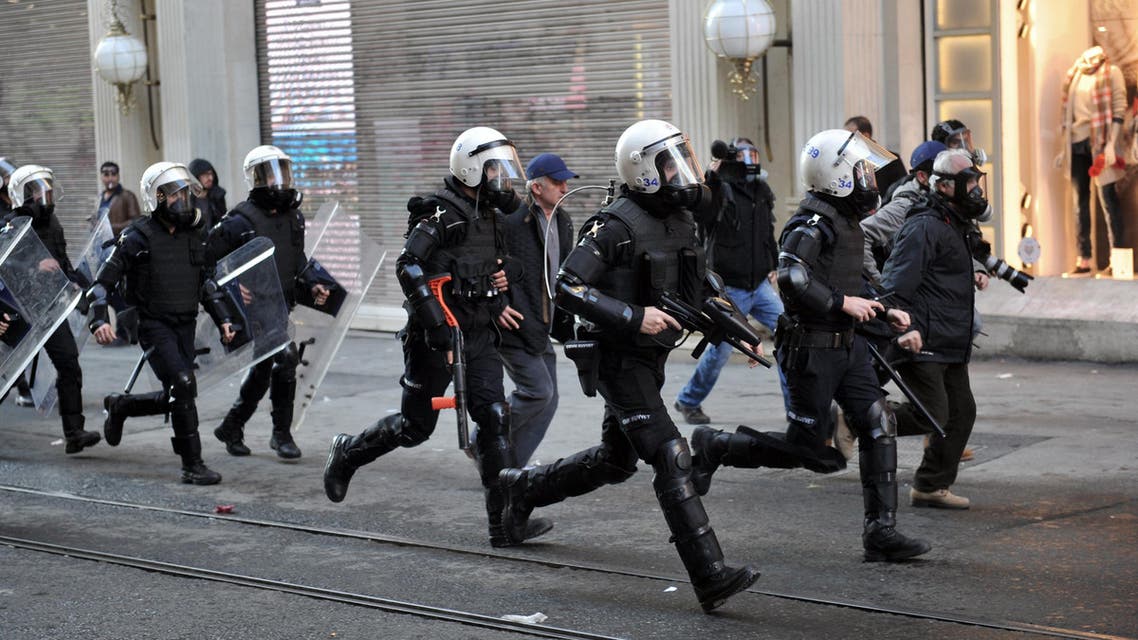 Police officers run to disperse people protesting against security operations against Kurdish rebels in southeastern Turkey, in Istanbul, Sunday, Dec. 20, 2015.