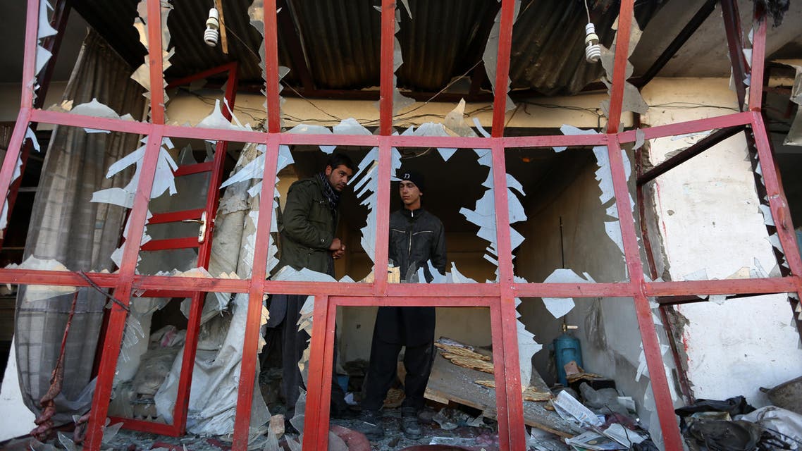 Afghan shopkeeper watches from a broken window of his shop near the site of suicide car bomb attack in Kabul, Afghanistan, Monday, Dec. 28, 2015.