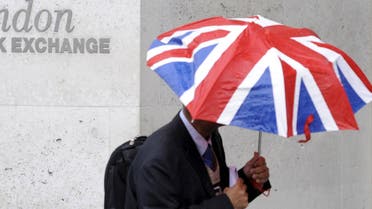 A worker shelters from the rain as he passes the London Stock Exchange in the City of London at lunchtime in this October 1, 2008 file photo.  (Reuters)