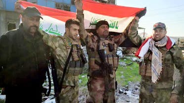 Iraqi soldiers hold national flags in the government complex in central Ramadi, 70 miles (115 kilometers) west of Baghdad, Iraq, Monday, Dec. 28, 2015. (AP)