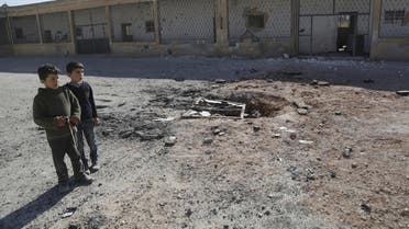 Boys stand at a ground damaged by what activists said were air strikes carried out yesterday by the Russian air force at a school in Jerjnaz town in Idlib. (Reuters)