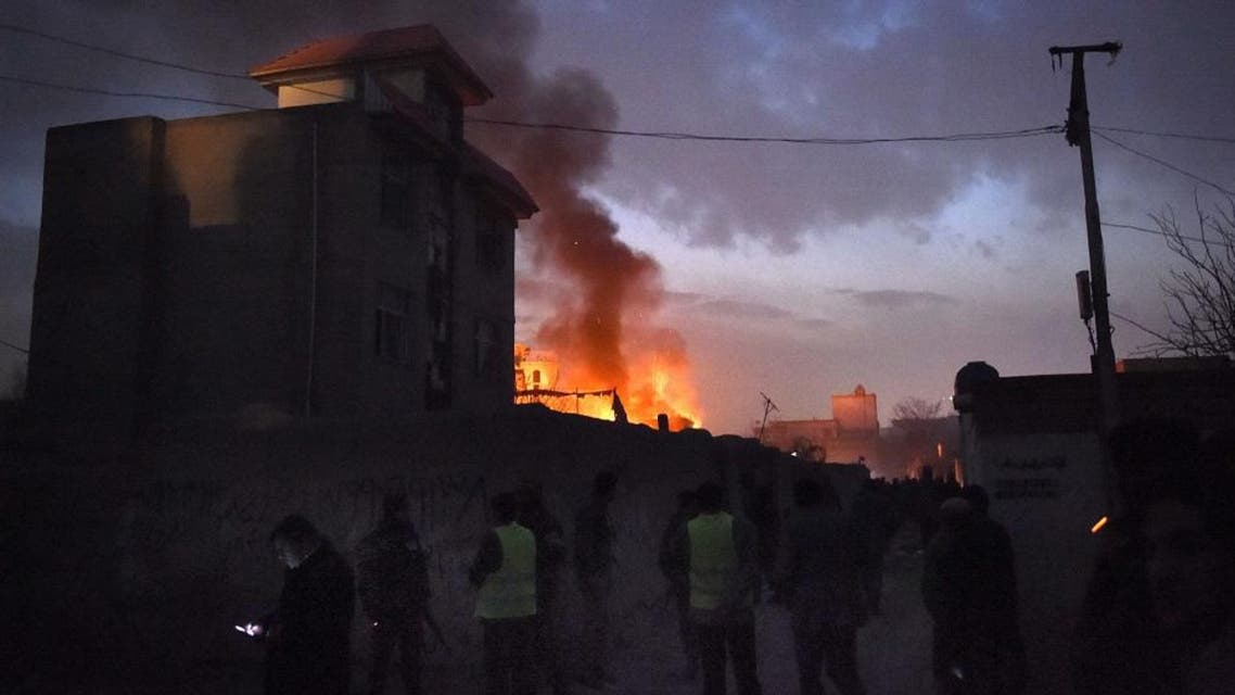 Security personnel and bystanders look on as flames and smoke rise at the site of a suicide car bomb attack at a French restaurant- Le Jardin in Kabul on January 1, 2016. A Taliban suicide car bomber raided a French restaurant popular with foreigners in Kabul, in a New Year's day attack that marks the latest in a series of brazen insurgent assaults.There was no immediate confirmation of casualties from the attack on Le Jardin, an Afghan-owned eatery, which caused a piercingly loud explosion and left a building engulfed in flames. AFP PHOTO/Wakil Kohsar