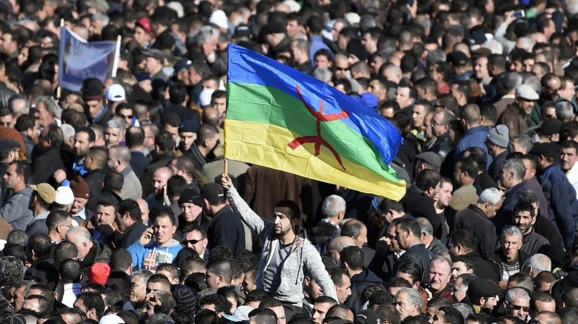 A man waves the Amazigh flag as thousands of mourners attend the funeral procession and burial of Hocine Ait-Ahmed, one of the fathers of Algeria's struggle for independence and a key opposition figure, in the Algerian village of Ait Ahmed on January 1, 2016. Ait-Ahmed's remains arrived in Algiers from Switzerland, where he died at the age of 89, for a state funeral the previous day before being transferred to his home village for his burial. The Amazighs, or Berbers, are the ethnicity indigenous to North Africa west of the Nile Valley. AFP PHOTO / FAROUK BATICHE