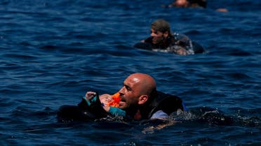 A Syrian refugee holding a baby swims towards the Greek island of Lesbos, September 12, 2015. (Reuters)