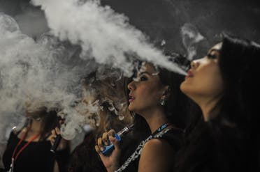 This picture taken on December 5, 2015 shows promoters smoking electronic cigarettes during the Vape Fair in Kuala Lumpur. (AFP)