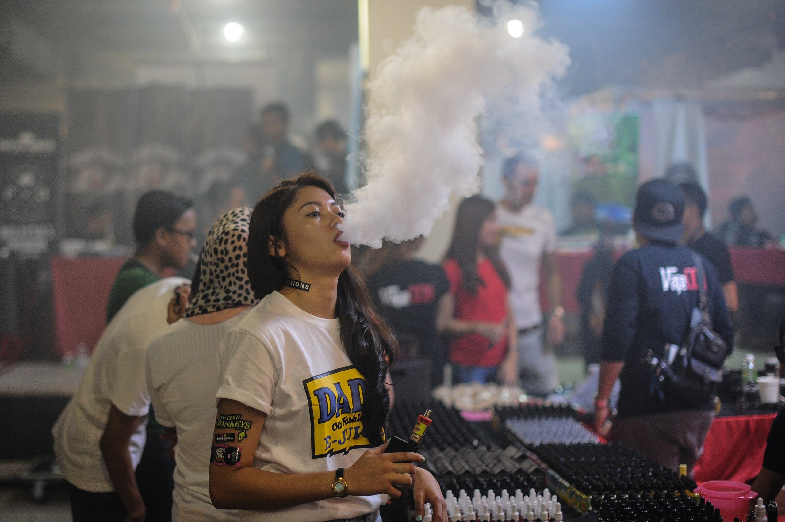 This picture taken on December 5, 2015 shows a promoter (C) smoking an electronic cigarette during the Vape Fair in Kuala Lumpur. afp