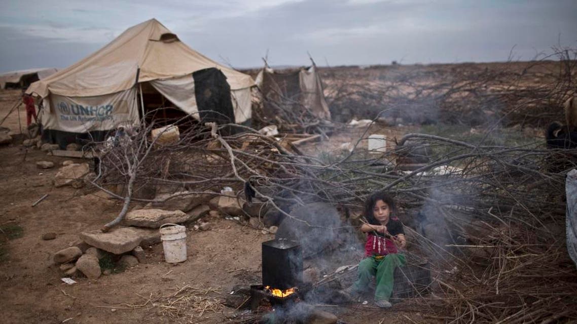 In this Oct. 23, 2015 file photo, Syrian refugee Aysha Elwan, 5, helps her mother in breaking wood to be added under a fire to boil water outside her family's tent at an informal tented settlement near the Syrian border on the outskirts of Mafraq, Jordan. The number of Syrian refugees stranded in a remote desert area known as "the berm," on the Jordanian border has tripled to 12,000 since last month, the U.N. refugee agency said Tuesday, Dec. 8, 2015. (AP Photo/Muhammed Muheisen, File)