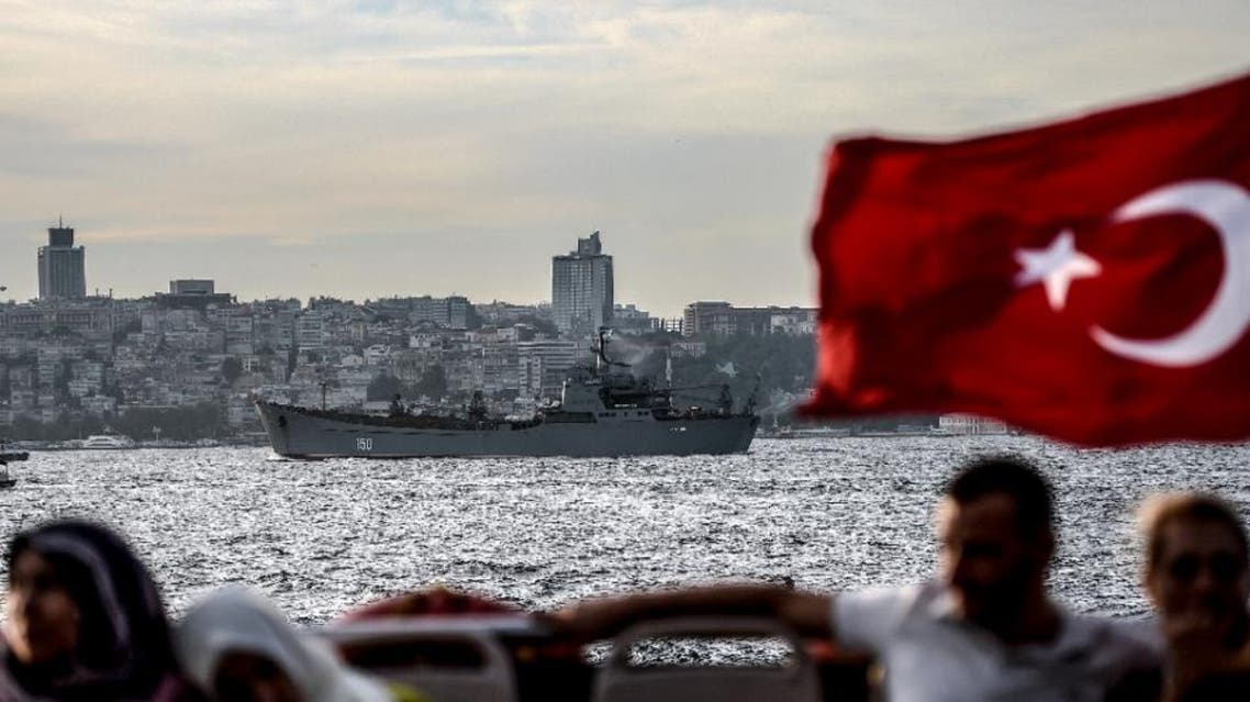 A Turkish flag flies on a ferry as Russian warship, the BSF Saratov 150, is seen sailing through the Bosphorus off Istanbul en route to the eastern Mediterranean sea (AFP Photo/OZAN KOSE)