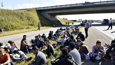 A group of refugees and migrants who were walking north sit down on the highway in southern Denmark on Wednesday, Sept. 9, 2015. The migrants have crossed the border from Germany, and after staying at a local school, they say they are now making their way to Sweden, to seek asylum. (Ernst van Norde/Polfoto via AP) 