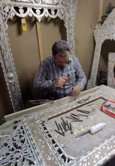 A Syrian artisan etches away at wooden panels inlaid with mother-of-pearl, at a workshop in the capital, Damascus, on December 1, 2015. AFP