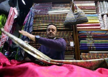 Bahaa al-Takriti, who weaves the richly embroidered aghbani cloths often used as table covers, shows off his products at his shop in the capital, Damascus, on December 1, 2015. AFP
