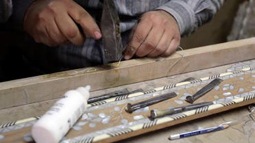 A Syrian artisan etches away at wooden panels inlaid with mother-of-pearl, at a workshop in the capital, Damascus, on December 1, 2015. (AFP)