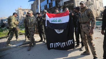 Members of the Iraqi security forces hold an Iraqi flag with an Islamic State flag which they had pulled down at a government complex in the city of Ramadi, December 28, 2015. REUTERS