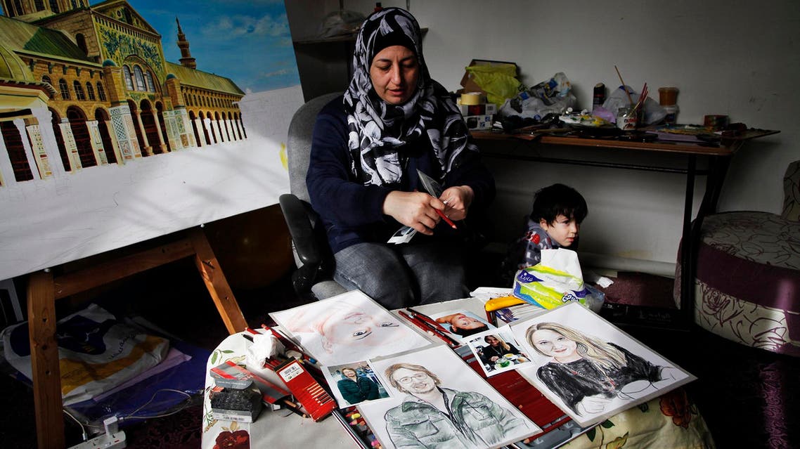 In this Thursday, Jan. 7, 2016 photo, Lina Mahameed, a Syrian artist and refugee from Daraa, works on portraits of some of the people killed in the Nov. 13 attacks in Paris by the Islamic State extremist group, in Amman, Jordan. One of Mahameed's three surviving children, six-year-old Rayan, stands nearby as she reviews photographs of victims she downloaded from the Internet. Mahameed, whose 16-year-old son Yasser was killed at the beginning of Syria’s civil war, hopes to send her portraits to the victims' families to show that “their tragedy is like our tragedy.” (AP Photo/Sam McNeil)