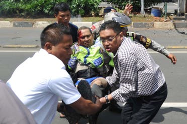  People carry an injured police officer near the site where an explosion went off at a police post, rear, in Jakarta, Indonesia Thursday, Jan. 14, 2016. Attackers set off explosions at a Starbucks cafe in a bustling shopping area in Indonesia's capital and waged gunbattles with police Thursday, leaving bodies in the streets as office workers watched in terror from high-rise windows. (AP Photo)