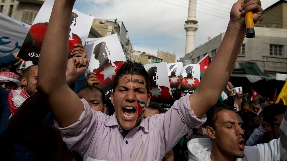 Demonstrators, one painting his national flag and Arabic that reads "Muath," chant anti-Islamic State group slogans and carry posters with pictures of slain Jordanian pilot, Lt. Muath al-Kaseasbeh, during an anti-IS group rally in Amman, Jordan, Friday, Feb. 6, 2015.