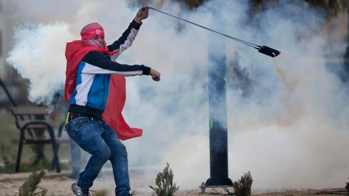 Palestinian demonstrators uses a slingshot to throw back a tear gas canister at Israeli troops following a rally marking the 48th anniversary of the founding of the Popular Front for the Liberation of Palestine (PFLP), in the West Bank, near Ramallah, Saturday, Dec. 12, 2015. (AP Photo/Majdi Mohammed)