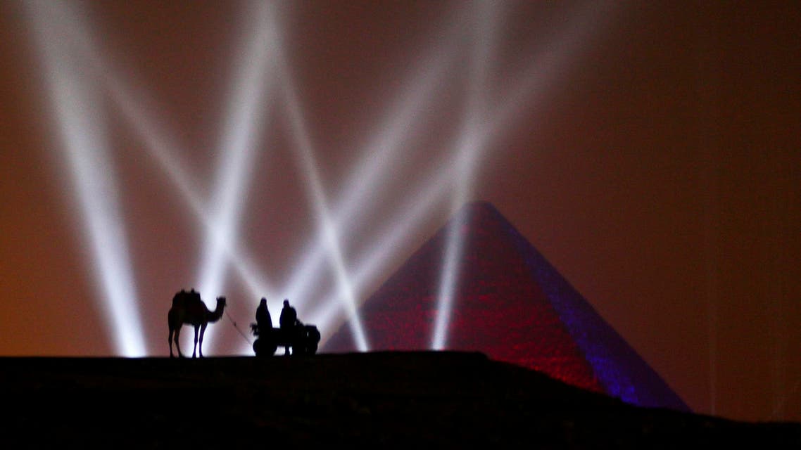  Two Egyptian men and a camel stand on a hill overlooking one of the Giza Pyramids during a New Year's Eve fireworks display near Cairo, Egypt at midnight on Friday, Jan. 1, 2016. (AP Photo/Maya Alleruzzo)