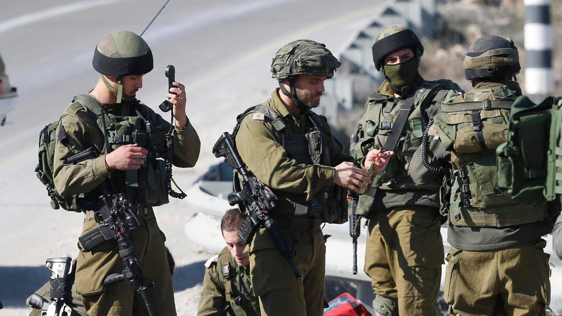 Israeli soldiers work around the body of a Palestinian assailant after he was shoot dead in the West Bank city of Hebron, Thursday, Dec. 24, 2015. (AP)