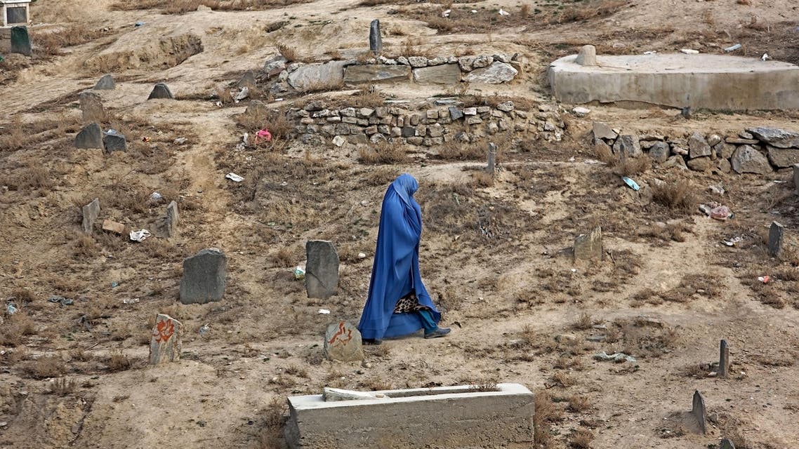 An Afghan woman walks at a cemetery in Kabul, Afghanistan, Tuesday, Dec. 8, 2015. (AP
