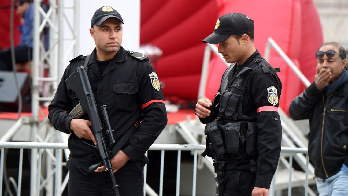 Tunisian policemen, wearing red armbands in protest over low wages and difficult working conditions, stand guard on Habib Bourguiba avenue in Tunis on January 18, 2016. / AFP