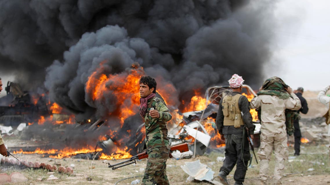 Shiite fighters known as Hashid Shaabi walk as smoke rises from an explosives-laden military vehicle driven by an Islamic State suicide bomber which exploded during an attack on the southern edge of Tikrit March 12, 2015. (Reuters)