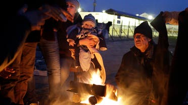 Refugees try to warm up around a fire at a refugee camp in the northern Greek village of Idomeni Thursday, Jan. 21, 2016. (AP)