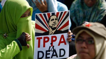  A Malaysian Muslim woman protestor poses for photograph holding an anti-TPPA (Trans-Pacific Partnership Agreement) placard with U.S. President Barack Obama's caricature during a protest in Kuala Lumpur, Malaysia, Saturday, Jan. 23, 2016. The Malaysian parliament is to hold a special sitting next week to debate on whether Malaysia should join the TPPA. (AP Photo/Joshua Paul)