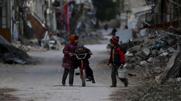 A girl pushes a boy on a bicycle past damaged buildings in Jobar, a suburb of Damascus, Syria January 23, 2016. (Reuters)