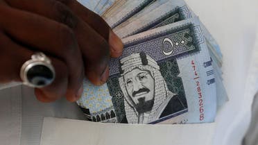 A Saudi man shows Saudi riyal banknotes at a money exchange shop, in Riyadh, Saudi Arabia January 20, 2016. (Reuters)