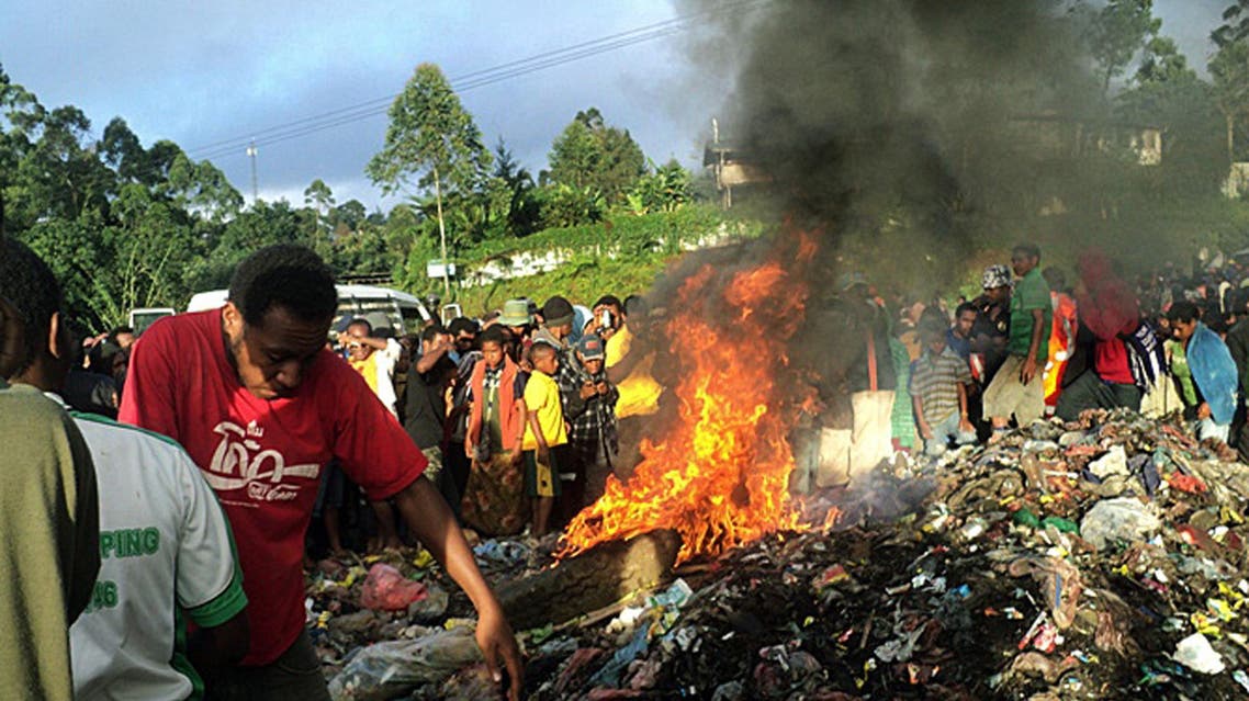 In this Wednesday, Feb. 6, 2013 photo, bystanders watch as a woman accused of witchcraft is burned alive in the Western Highlands provincial capital of Mount Hagen in Papua New Guinea. The 20-year-old mother of one, Kepari Leniata was stripped naked by several assailants, tortured with a hot iron rod, bound, doused in gasoline, then set alight on a pile of car tires and trash. (AP Photo/Post Courier) PAPUA NEW GUINEA OUT