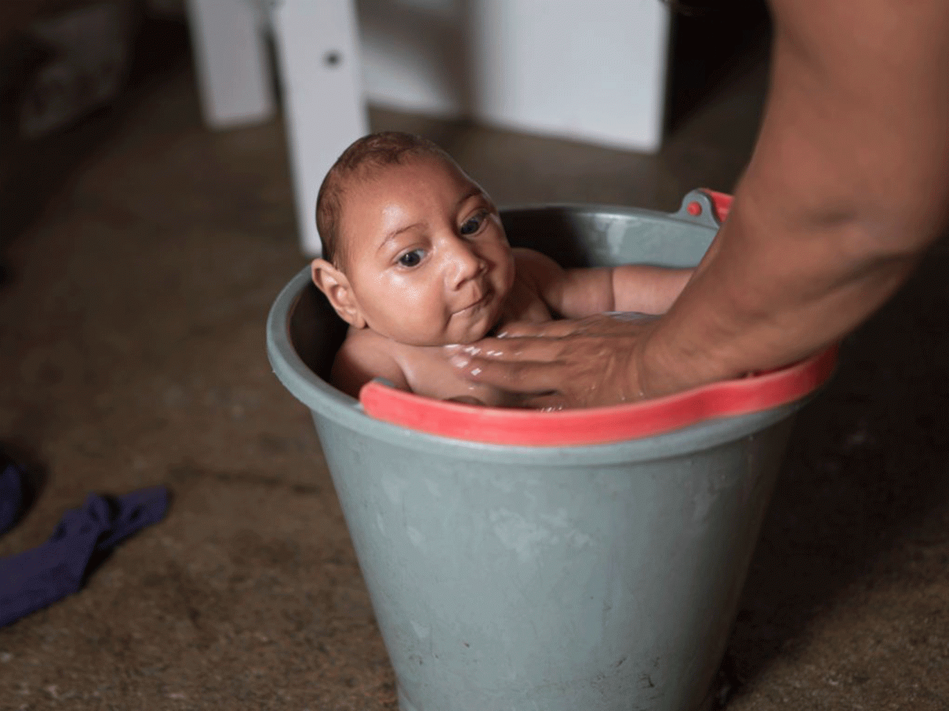 Solange Ferreira bathes her son Jose Wesley in a bucket of water, which she says he enjoys and helps calm him, at their home in Poco Fundo, Brazil. (AP)