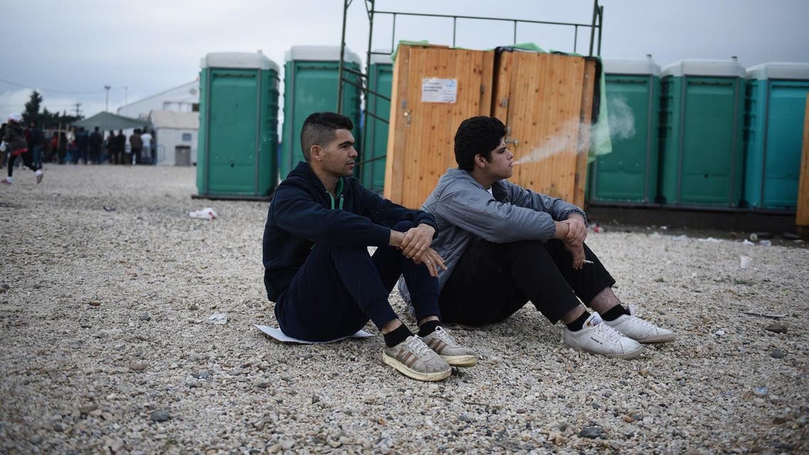 Refugees smoke at a refugee camp, as they wait to be allowed to pass from northern Greek village of Idomeni, to southern Macedonia. (AP)