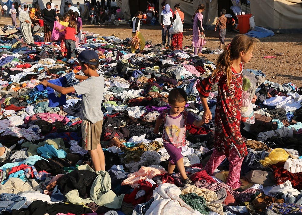 Displaced Iraqis from the Yazidi community look for clothes to wear among items provided by a charity organization at the Nowruz camp, in Derike, Syria, Tuesday, Aug. 12, 2014. In the camps here, Iraqi refugees have new heroes: Syrian Kurdish fighters who battled militants to carve an escape route to tens of thousands trapped on a mountaintop. While the U.S. and Iraqi militaries dropped food and water to the starving members of Iraq’s Yazidi minority, the Kurds took it on themselves to rescue them, a sign of how Syria’s Kurds, like Iraq’s, are using the region’s conflicts to establish their own rule. (AP Photo/ Khalid Mohammed)