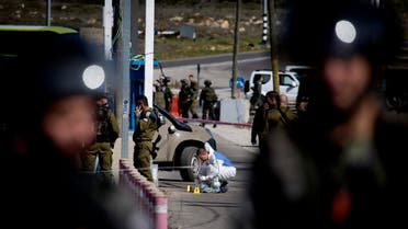 Israeli security forces inspect the site next to the body of a Palestinian identified as Amjad Sukkari, at the checkpoint between the city of Ramallah and Jewish settlement of Beit El in the West Bank, Sunday, Jan. 31, 2016. AP