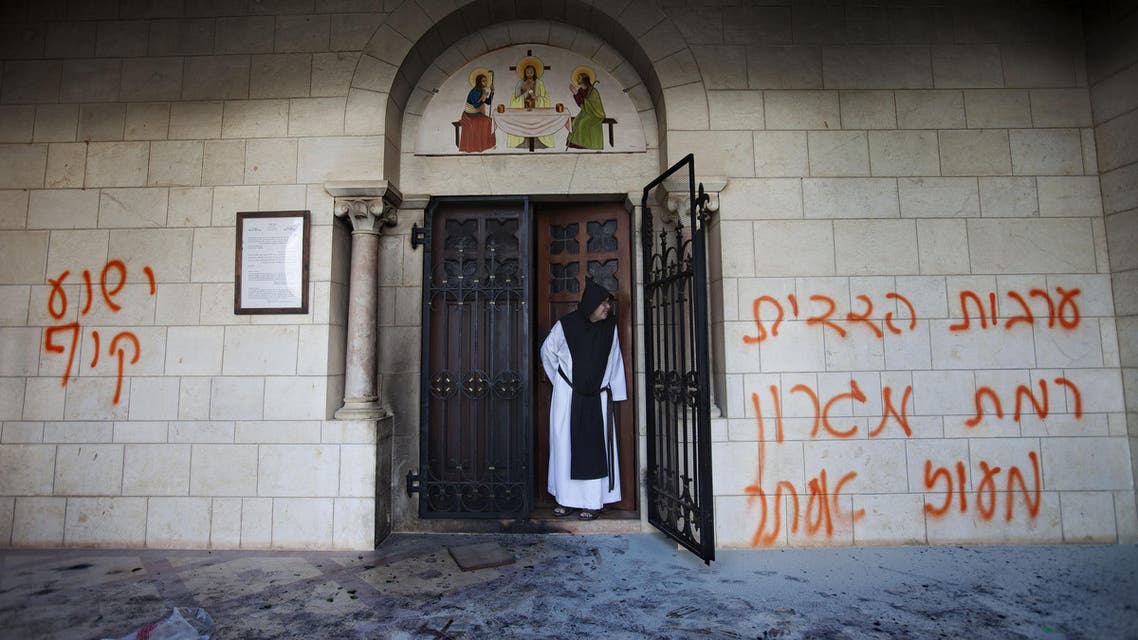 A catholic monk stands in a doorway of the Latrun Trappist Monastery where Israeli police say vandals overnight have spray-painted anti-Christian and pro-settler graffiti and set the monastery's door on fire, in Latrun, between Jerusalem and Tel Aviv, Israel, Tuesday, Sept 4, 2012.