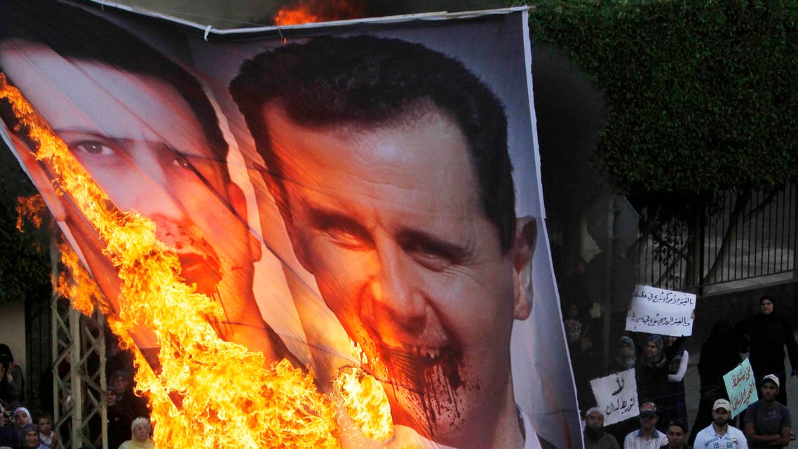 Protesters chant slogans against the Syrian regime and Russia's support of President Bashar Assad as they burn a banner depicting Assad, top, his brother, Maher Assad and Russian President Vladimir Putin, bottom, in the southern port city of Sidon, in Lebanon, Sunday, June 17, 2012. (AP Photo/Mohammed Zaatari)