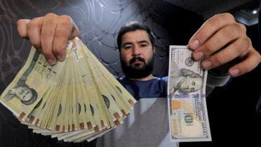 File photo of money changer posing for the camera with a U.S dollar and the amount being given when converting it into Iranian rials, at a currency exchange shop in Tehran's business district. (Reuters)