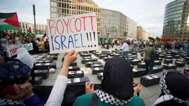 A woman holds a sign which reads "Boycott Israel" in front of symbolic coffins while attending a demonstration supporting Palestine, in Berlin. (File photo: Reuters)