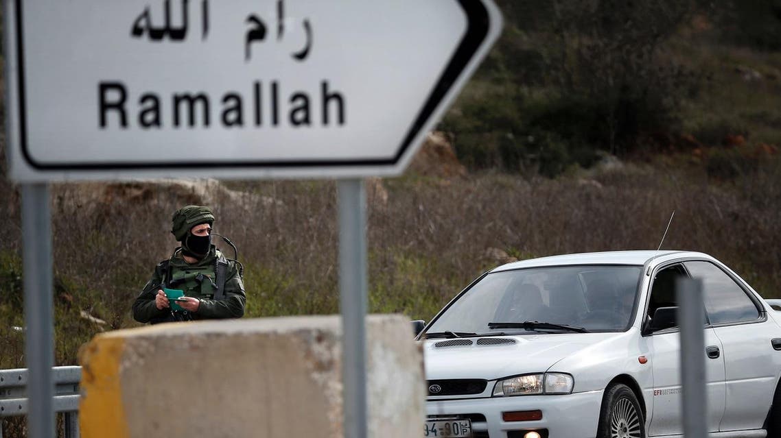 An Israeli soldier checks the documents of the passengers of a Palestinian car on a road leading to the West Bank village of Ein Sinya, northern Ramallah. (AFP)