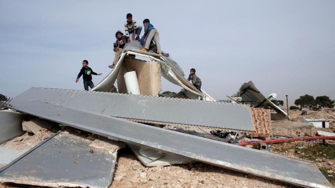 Palestinian Bedouins play around the remains of makeshift homes that were demolished by the Israeli army in the West Bank city of al-Azariya, on January 21, 2016 (AFP)