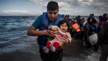 A man holding a baby disembarks from a dinghy after arriving from a Turkish coast to the northeastern Greek island of Lesbos. (File photo: AP)
