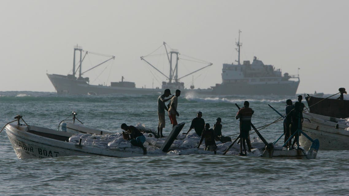 Somali men carry food aid on small boats where they off-loaded food from the cargo ship Victoria, background,, Tuesday, Dec. 18, 2007 in the Somali town of Merka, some 60 miles south of Mogadishu. AP
