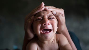 In this Jan. 30, 2016 photo, Elielson tries to calm down his baby brother Jose Wesley, in Bonito, Pernambuco state, Brazil.